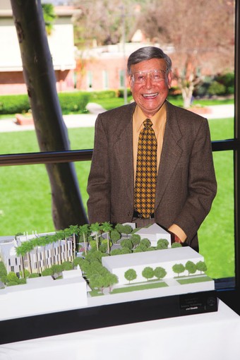 Alton Lim smiling and standing next to a model of a building