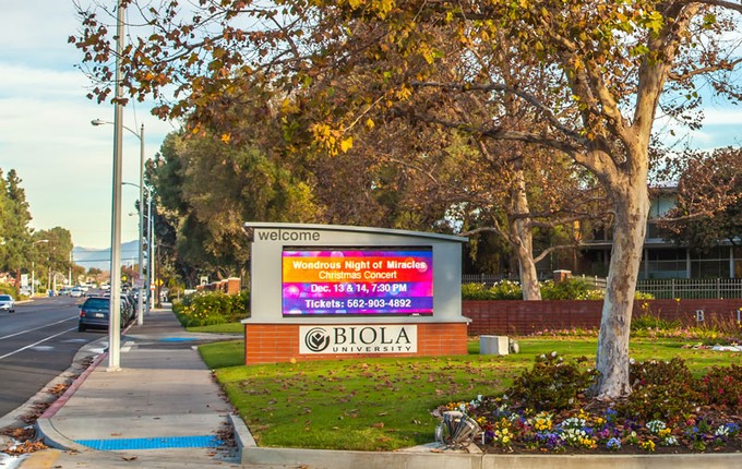 a digital marquee next to trees and a road