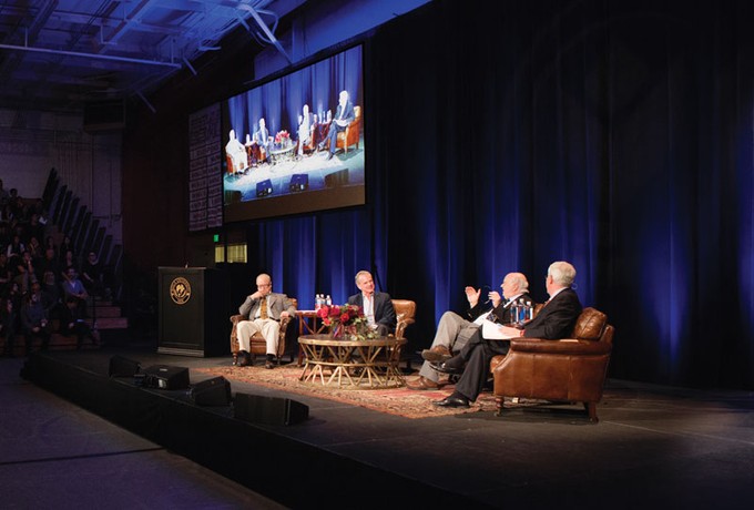 a stage with four men sitting and talking