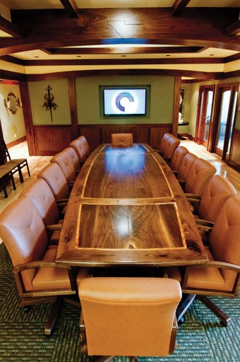 a large wooden table surrounded by chairs with a tv on a wall