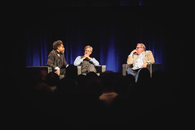 Three men sitting and talking on a stage