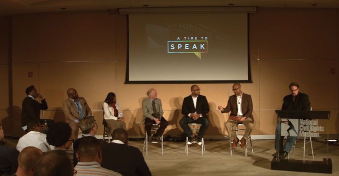 a panel of speakers on a stage