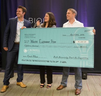 two young men and a young woman holding an oversized check