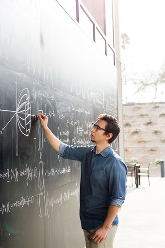 A young man writing on an outdoor chalkboard