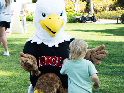 a person dressed in an eagle costume extending arms to a child