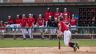 A baseball player with a bat in hand beginning to run