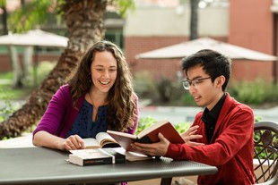 A professor and a student looking at books outside